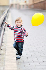 Adorable little boy  with yellow baloon in heand