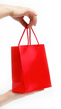 Red gift bag in the women's hands on a white background.