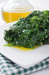 Boiled spinach on white dish. Spinaci bolliti.