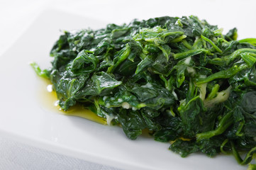 Boiled spinach on white dish. Spinaci bolliti.