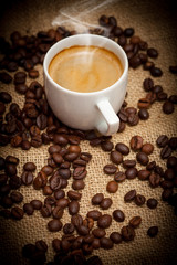 Close-up cup of hot coffee and coffee beans