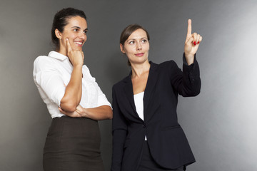 Zwei Geschäftsfrauen drücken auf einen virtuellen Schirm