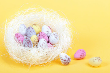 Easter eggs in a white nest, on yellow background