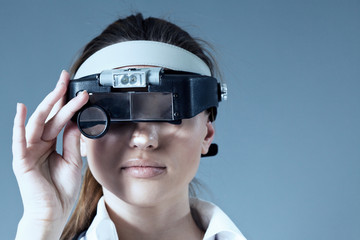 Young female doctor wearing magnifying glass equipment