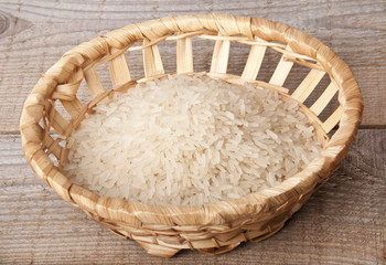 Fototapeta na wymiar Rice in a wattled plate, on a wooden background