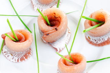 Rolls of marinated herring close up with spring onion