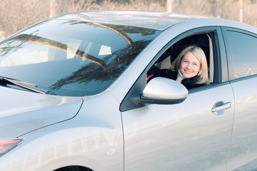 Smiling blonde behind the wheel of the car on a winter road