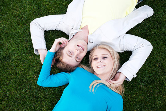 Happy Young Couple Lying On Grass In Love