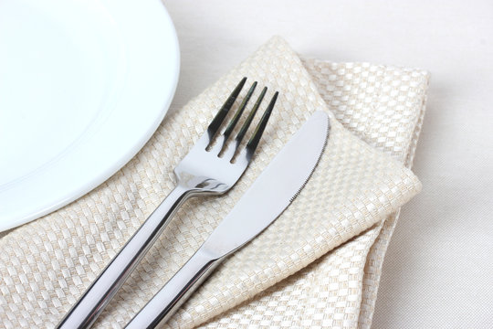 fork, knife on napkin and plate isolated on white