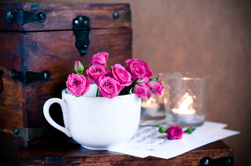 bouquet of roses in a cup, candles, notes