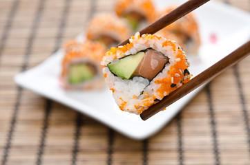 Chopsticks holding sushi roll