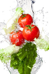 Three Fresh red Tomatoes and lettuce in splash water Isolated on