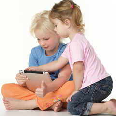 Two cute children sitting on the floor and playing with touchpad