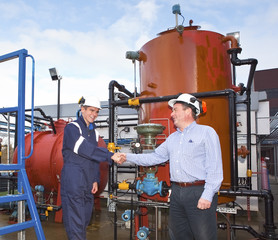 Two petrochemical contractors closing a deal in front of an oil