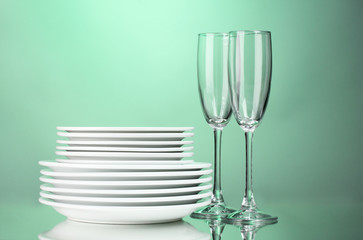 Clean plates and glasses on green background