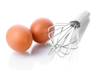Metal whisk for whipping eggs and brown eggs isolated on white