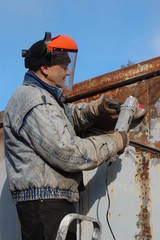 Man works with angular electric grinder