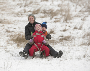 Happy family slides with sledge on snowy hill