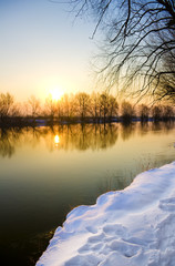 Fototapeta na wymiar Zachód słońca nad zamarzniętą rzekę