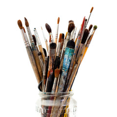 Assorted dirty painting brushes in glass flask