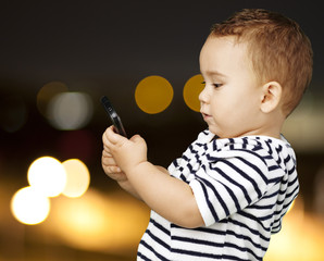 portrait of funny kid touching mobile at city by night