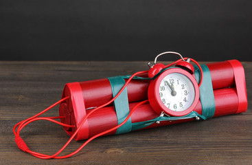 Timebomb made of dynamite on wooden table on grey background