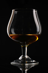 Glass of cognac on black background