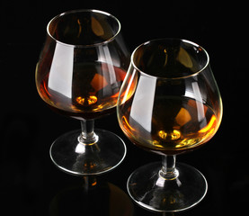 Two glasses of cognac on black background
