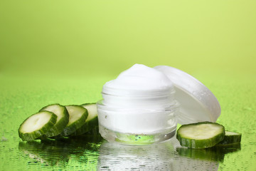 cream and fresh sliced cucumber on green background
