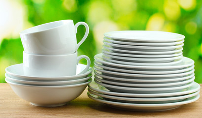 Clean dishes on wooden table on green background
