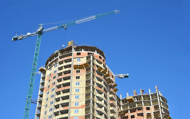 Building crane and building under construction against blue sky