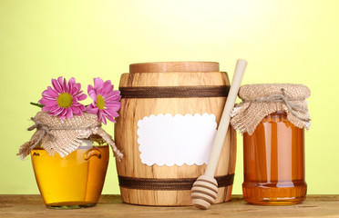 Fototapeta na wymiar Sweet honey in jars and barrel with drizzler