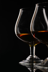 Two glasses of cognac on black background