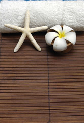 Fototapeta na wymiar Bowl of frangipani flowers and towel on bamboo mat
