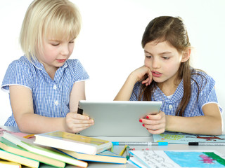 Two cute girlfriends learning with books and touchpad