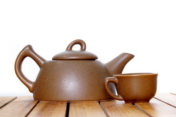 teapot and cup on wooden table over white
