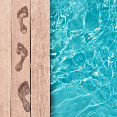 Traces de pieds nus sur un deck en bois,au bord d'une piscine, concept été © Delphotostock