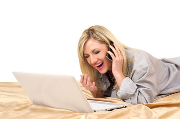 Blonde woman working with laptop on bed