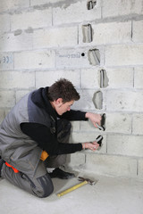 Electrician routing wiring through wall