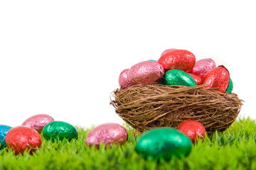 Colorful Easter eggs in nest on fresh grass, isolated on white