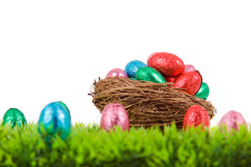 Colorful Easter eggs in nest on fresh grass, isolated on white