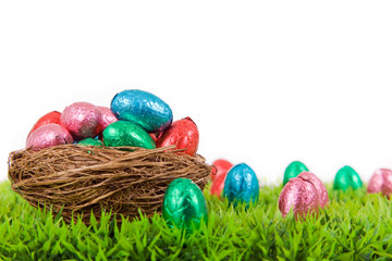 Colorful Easter eggs in nest on fresh grass, isolated on white