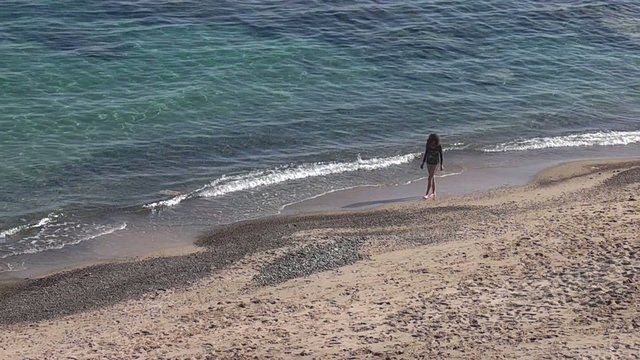 CHICA RECOGIENDO PIEDRAS EN LA ORILLA DEL MAR