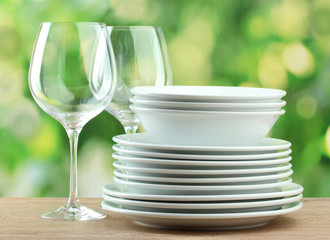 Clean dishes on wooden table on green background