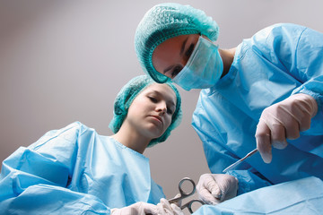 Below view of surgeons holding medical instruments in hands