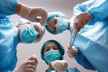 Below view of surgeons holding medical instruments in hands