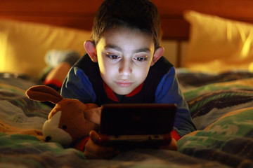 kid in bed wih videogame console