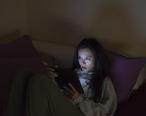 Young woman reading a tablet in the dark