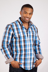 Black man in plaid shirt with hands in his pockets