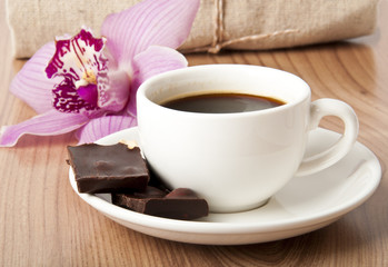 cup of coffee, chocolate and orchid on wooden background